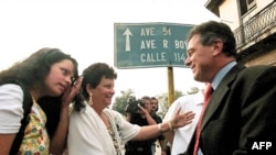 Magalys de Armas, esposa del opositor Vladimiro Roca, y su hija saludan a Michael Georges Kozak(R), en el Tribunal Municipal de Marianao. AFP/ADALBERTO ROQUE 