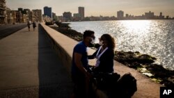 Una pareja de enamorados se proteje del coronavirus en el Malecón de La Habana.