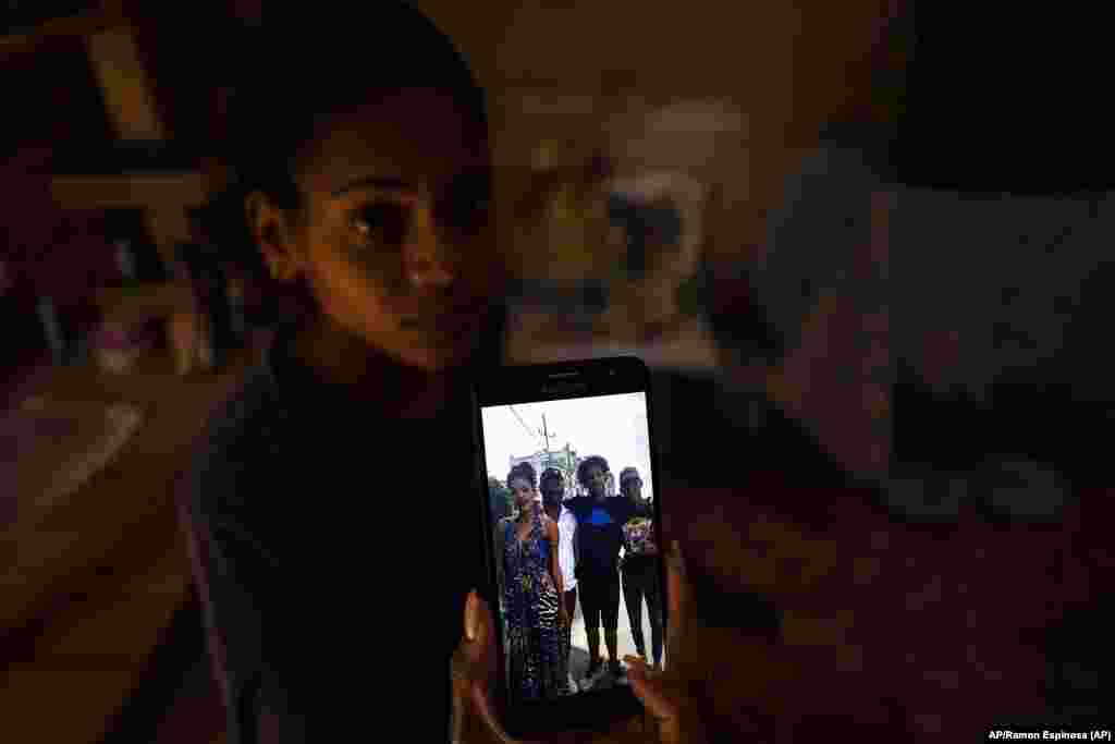 Mar&#237;a Carla Mil&#225;n Ramos muestra una foto en su tel&#233;fono de su esposo con sus hermanos, detenidos por participar el 11 de julio.
