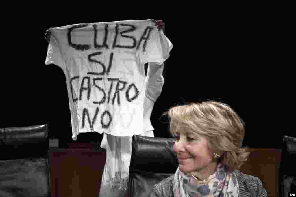 La presidenta del PP de Madrid, Esperanza Aguirre (d), mientras una participante muestra una pancarta durante el acto organizado hoy en la Casa de América de Madrid bajo el título "Damas de Blanco: Un mensaje de Cuba". En el acto se ha producido un enfren