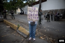 Una mujer sostiene un cartel en el que se lee "Yo soy Óscar Pérez" frente a la morgue en donde está cuerpo del exagente.