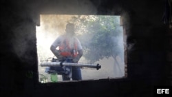 Un trabajador de la salud fumiga una casa para combatir el dengue