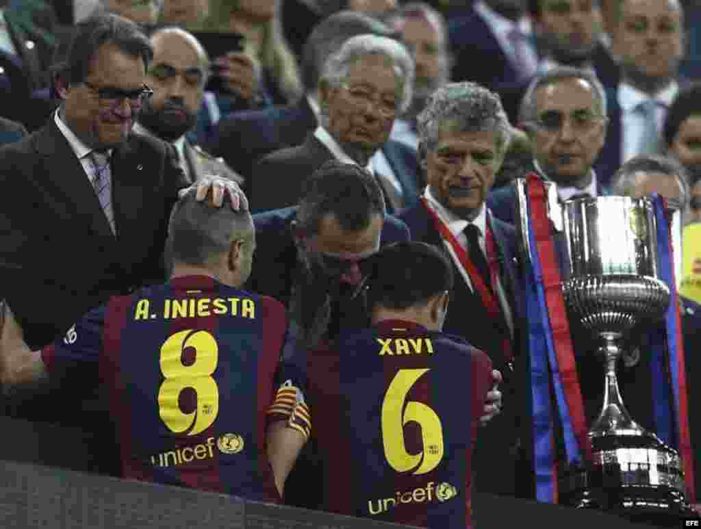 El rey Felipe, junto al presidente de la Generalitat, Artus Mas (i), y el presidente de la Federación Española de Fútbol, Ángel María Villar (d), felicita a los jugadores del FC Barcelona Xavi Hernández y Andrés Iniesta tras ganar el partido de la final de la Copa del Rey.