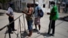 En esta foto tomada el 8 de julio en la barrera de acceso a un barrio habanero, un policía habla con personas que se disponían a pasar a una zona restringida (Foto: Alexandre Meneghini/Reuters).