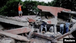 Un rescatista levanta los puños para pedir silencio mientras se localiza a las víctimas bajo los escombros de un edificio derrumbado tras el simo, Cali, Colombia.