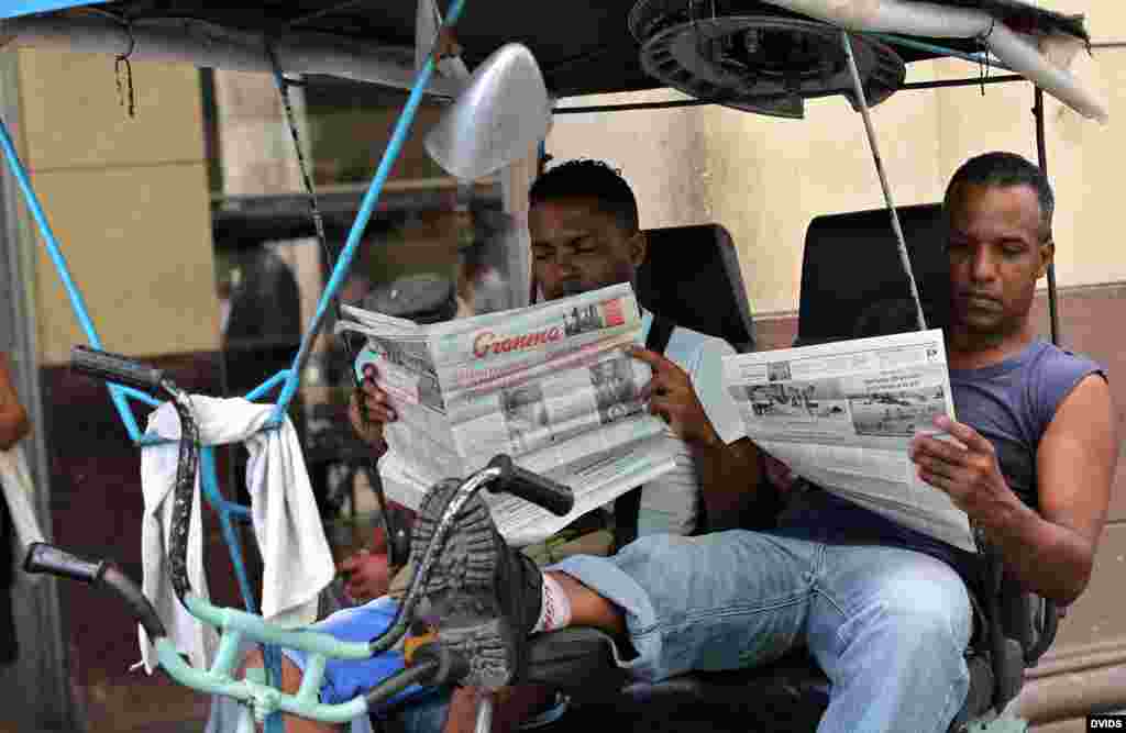  Dos bicitaxistas leen el Granma, en La Habana, Cuba.