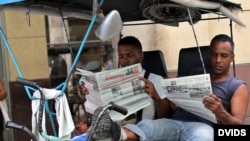 Dos bicitaxistas leen el Granma, en La Habana, Cuba.