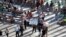 Un hombre muestra un cartel junto a decenas de curiosos y periodistas frente a la embajada de Estados Unidos en Cuba.