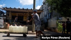 Cubanos cargan tanques de agua en una carretilla en La Habana. Foto: REUTERS/Norlys Pérez