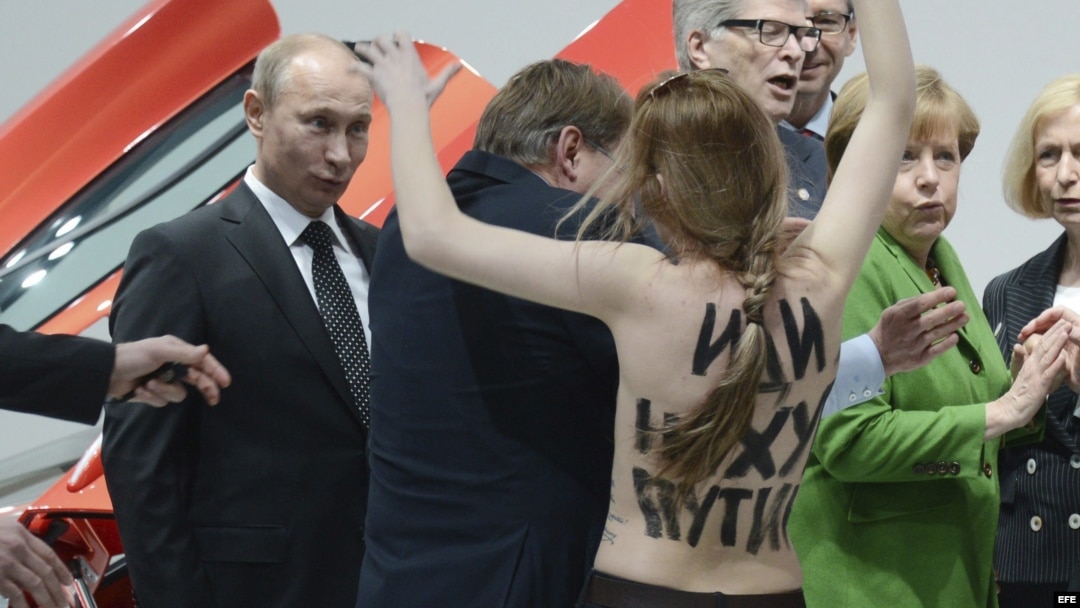 Vladimír Putin (i), y la canciller alemana, Angela Merkel (2-d), se ven sorprendidos por una activista de Femen en topless durante su visita a la Feria Industrial de Hanover, Alemania. 
