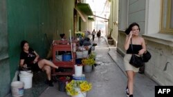 Una mujer camina mientras habla por teléfo calle de Santa Clara, provincia de Villa Clara, Cuba, el 11 de septiembre de 2023. (Foto de ADALBERTO ROQUE / AFP)