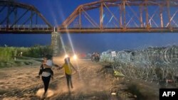 Migrantes caminan después de cruzar el Río Grande en la frontera entre Estados Unidos y México en Eagle Pass, Texas, el 22 de septiembre de 2023. (Foto de Paula RAMON / AFP)