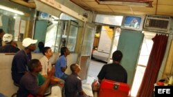 Un grupo de seguidores siguen un evento deportivo en una barbería de La Habana Vieja.