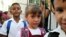  Tres niños posan con una bandera cubana durante el primer día del curso escolar.