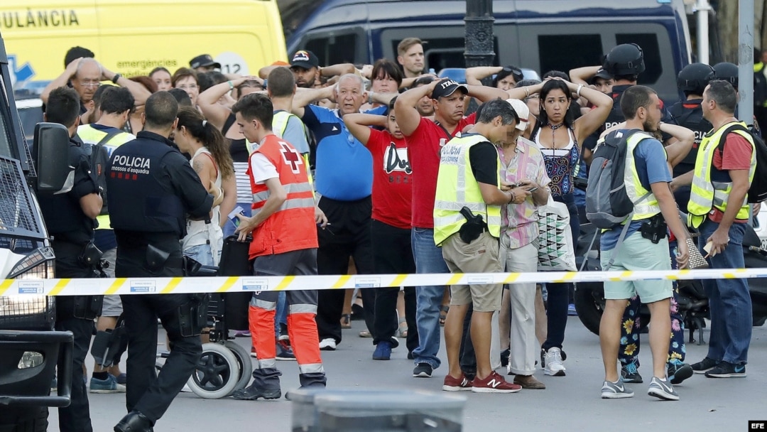 Un grupo de gente con los brazos en alto ante el despliegue policial en el lugar del atentado ocurrido hoy en las Ramblas de Barcelona.