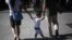 Padres chinos llevan de la mano a su hijo en un parque de Pekín (China). 