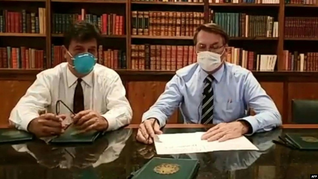 Jair Bolsonaro (derecha) usando una mascara protectora contra el coronavirus en un programa de TV.