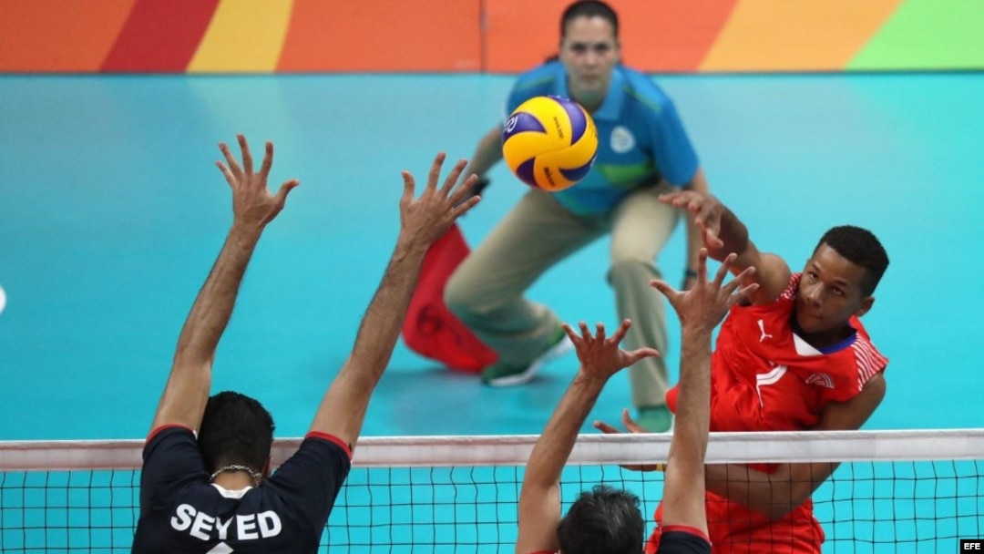 El cubano Osniel Melgarejo (d) golpea el balón ante los iraníes Seyed Mohammad Mousavi Eraghi (i) y Mir Saeid Marouflakrani (c) el 11 de agosto de 2016, durante el partido de voleibol que disputaron ambos equipos en los Juegos Olímpicos Río 2016. 