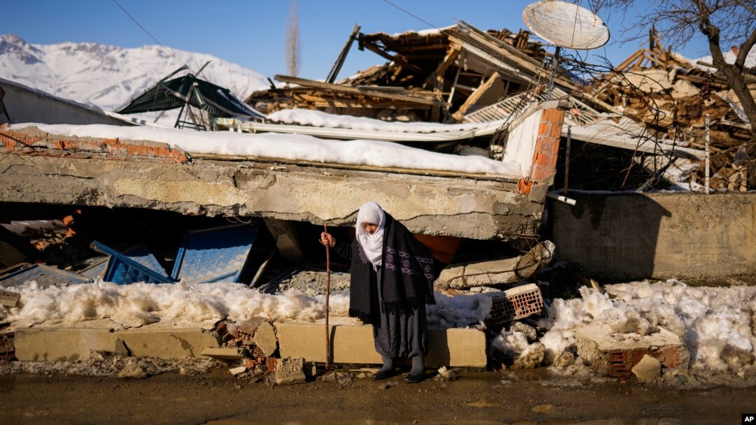 Zehra Kurukafa pasa junto a una casa destruida en la localidad de Polat, Turquía, el domingo 12 de febrero de 2023. (AP Foto/Francisco Seco)