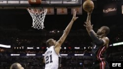  Dwyane Wade (d) se alza por encima del bloqueo de Tim Duncan (centro). Wade estuvo imparable, llevando 32 puntos al marcador.