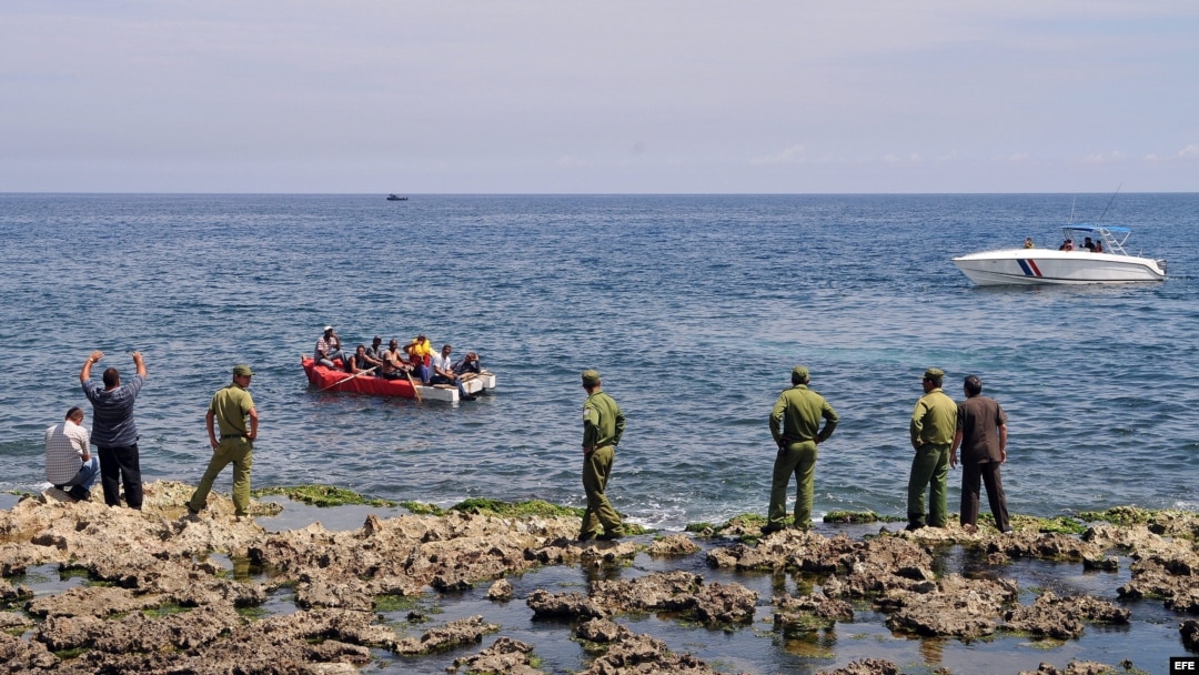 Guardafronteras observan a un grupo de cubanos a bordo de una embarcación rústica que intenta salir por mar hacia Estados Unidos.
