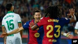 Robert Lewandowski, del Barcelona, (centro) celebra con Jules Kounde tras marcar el primer gol durante un partido entre el Barcelona y el Getafe en el Estadio Olímpico de Barcelona, España, 25 de septiembre de 2024. (AP Photo/Joan Monfort)