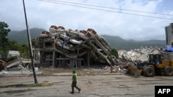 A member of the Venezuelan National Guard walks past the collapsed remains of a residential building that collapsed following the June 24, 2026 earthquakes, in Caraballeda, Venezuela, on July 20, 2026. (Photo by Federico PARRA / AFP)