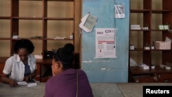 Una mujer compra medicamentos en una farmacia junto a un cartel que anuncia las próximas elecciones legislativas, en el centro de La Habana, Cuba, 17 de marzo de 2023. REUTERS/Alexandre Meneghini