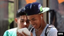 Dos jóvenes navegan por internet desde un dispositivo móvil hoy, viernes 3 de julio del 2015, en una de las zonas habilitadas con Wi-Fi en La Habana.