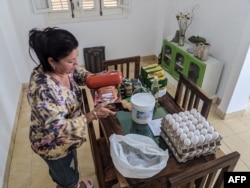 María Páez, de 59 años, organiza la comida que sus hijos le enviaron desde Miami a través de un distribuidor de remesas de alimentos en La Habana el 16 de mayo de 2024.