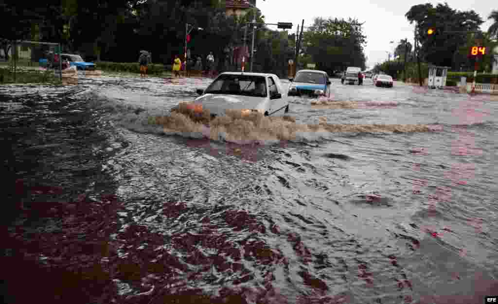  Vehículos transitan por una calle inundada en La Habana (Cuba). 