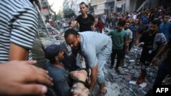 Varias personas evacuan el cadáver de un hombre del lugar donde se produjo un ataque israelí contra la ciudad de Gaza el 10 de octubre de 2023. (Foto de Bashar TALEB / AFP)