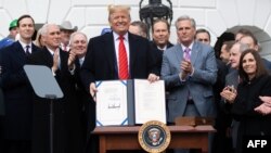 Donald Trump muestra el acuerdo firmado con México y Canada. SAUL LOEB / AFP