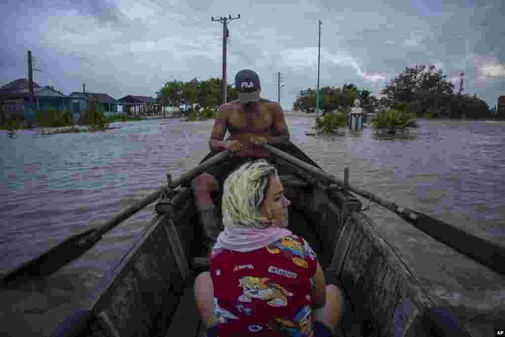 Cubanos recorren una calle inundada en un bote de madera en Guanimar, provincia de Artemisa, donde varias localidades quedaron bajo el agua tras el pasod el huracán Helene, el miércoles 25 de septiembre de 2024. (Foto AP/Ramon Espinosa)