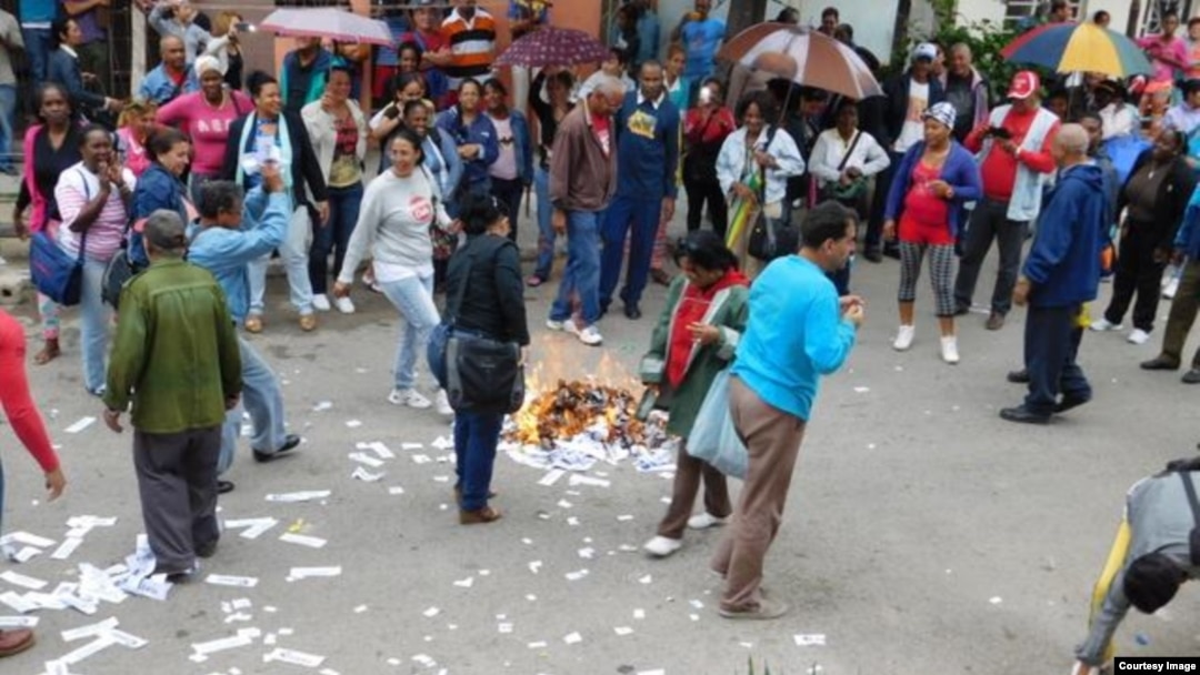 Las brigadas de Respuesta Rápida queman ejemplares de la Declaración Universal de los Derechos Humanos, lanzados a la calle por las Damas de Blanco. (Foto: Ángel Moya.