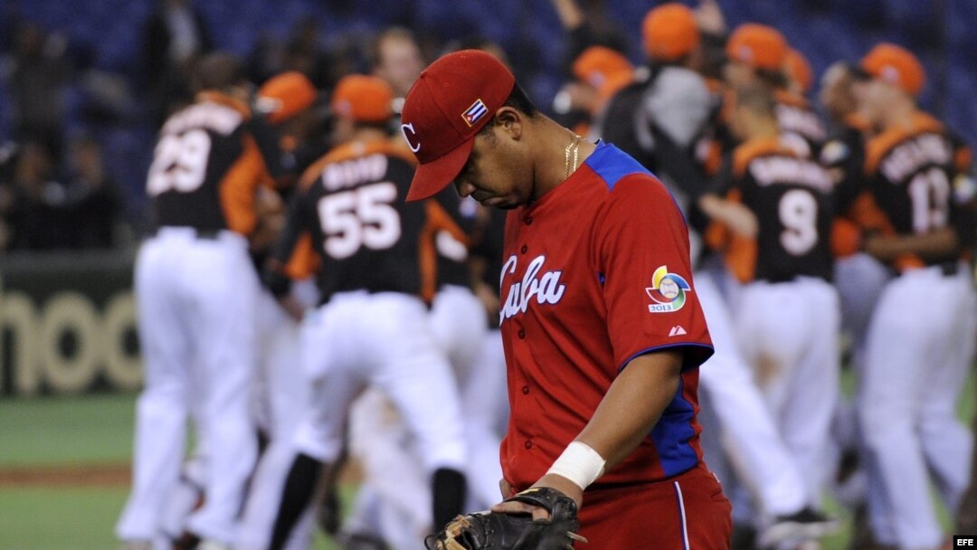 El jugador cubano Jose Abreu pasa delante del equipo holandés, que se encuentra celebrando su victoria tras imponerse a Cuba en el Clásico Mundial de Béisbol disputado en el estadio Tokyo (Japón). 