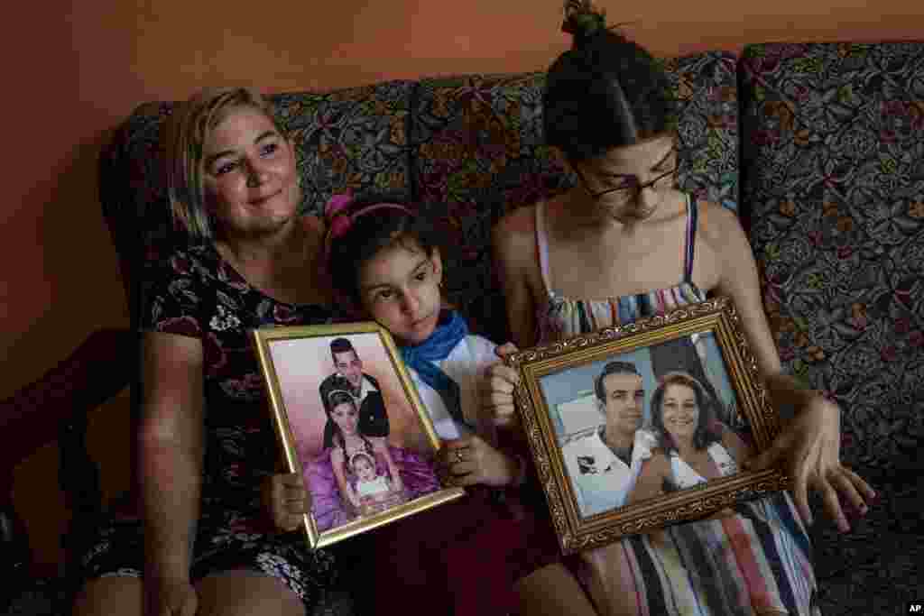 Danmara Triana (izquierda), con sus hijas Alice (centro) y Claudia, muestran fotos suyas con su hermano y su padres, quienes se mudaron a Estados Unidos en 2015. &nbsp;(AP Foto/Ramón Espinosa)