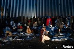Inmigrantes en Sonora mientras esperan el transporte de la Patrulla Fronteriza en la frontera entre Estados Unidos y México cerca de Lukeville, Arizona, Estados Unidos, el 25 de diciembre de 2023.