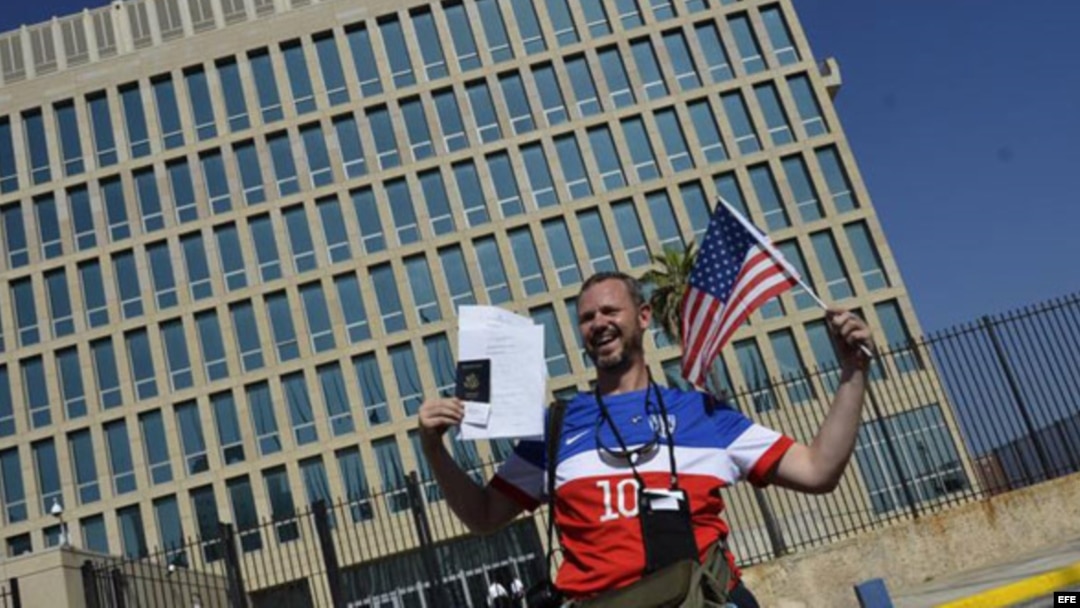 Un hombre posa con sus documentos migratorios frente a la Embajada de EEUU.