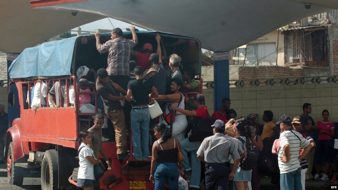 Varias personas intentan subir a un camión particular que funciona como transporte público en Santiago de Cuba. EFE