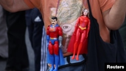 Un seguidor de Nicolás Maduro y Cilia Flores carga estatuillas con su apariencia vestidas de superhéroes, en New York, el 26 de marzo. 