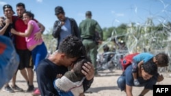 Una familia de inmigrantes después de romper una barricada de alambre de púas hacia los Estados Unidos, después de horas de espera en el Río Grande, en Eagle Pass, Texas, el 25 de septiembre de 2023. ANDREW CABALLERO-REYNOLDS / AFP.