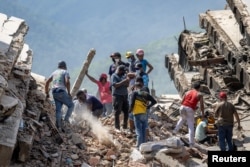 Voluntarios y residentes buscan entre los escombros de un edificio colapasado en Caraballeda, La Guaira, el 28 de junio de 2026.