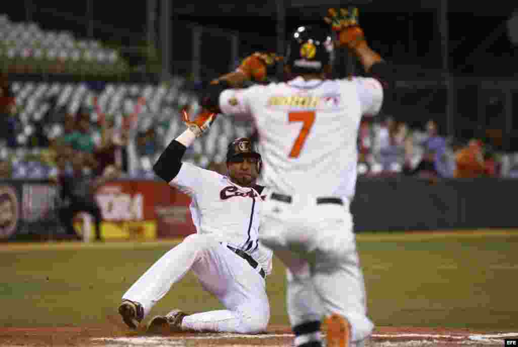 El jugador venezolano Jose Castillo (atrás) en acción durante la semifinal entre Cuba y Venezuela por la Serie del Caribe de Béisbol,