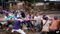 Ciudadanos ayudando después de que las fuertes lluvias provocaran el desbordamiento de un río en Las Tejerías, Venezuela, el domingo 9 de octubre de 2022.