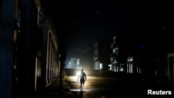 Un hombre camina por una calle oscura mientras la red eléctrica de Cuba colapsaba a última hora del domingo, sumiendo a la isla en la oscuridad.