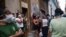 Cubanos se protegen con máscaras durante la espera para comprar en una tienda en La Habana.