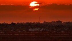 Esta imagen, tomada desde una posición en la frontera israelí con la Franja de Gaza, muestra el sol poniéndose tras edificios en el territorio palestino el 10 de junio de 2026. (Foto de Jack GUEZ / AFP)