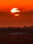 Esta imagen, tomada desde una posición en la frontera israelí con la Franja de Gaza, muestra el sol poniéndose tras edificios en el territorio palestino el 10 de junio de 2026. (Foto de Jack GUEZ / AFP)