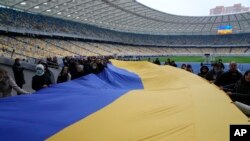 Una bandera ucraniana de 200 metros se despliega en el Estadio Olímpico de Kiev, Ucrania, el 16 de febrero de 2022. (AP Foto/Efrem Lukatsky)